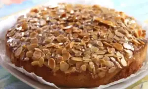Gâteau aux amandes, doré et croustillant, garni de lamelles d'amandes grillées sur un glaçage brillant.