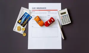 Documento di assicurazione auto, denaro, carte di credito e macchinina. È obbligatorio avere il certificato di assicurazione in auto.