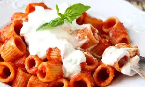 En krämig portion rigatoni med tomatsås och en generös klick stracciatella pasta, toppad med färsk basilika.