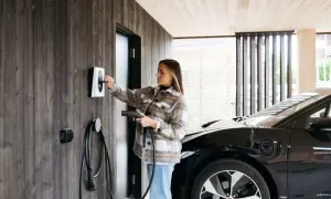 Kvinna laddar elbil vid laddbox. Frågan "hur lång tid tar det att ladda en elbil 22kw" är relevant här.