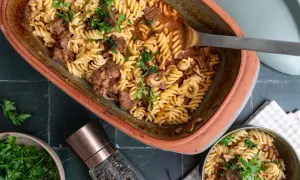 Herzhaftes Gulasch mit Nudeln, garniert mit frischer Petersilie, serviert in einem rustikalen Auflauf.