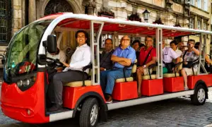 Eine Gruppe von Touristen genießt eine entspannte Stadtrundfahrt in Breslau mit einem roten Elektro-Tourbus.