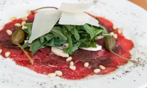 Delicato carpaccio di manzo con rucola, scaglie di parmigiano, pinoli, capperi e funghi champignon.