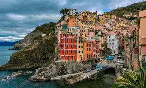 Kolorowe **miasta Cinque Terre** wznoszą się na skalistym wybrzeżu Ligurii. Domy przytulone do klifu, łodzie przy brzegu.