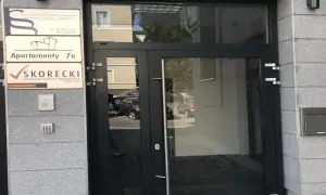 Drzwi wejściowe do budynku z tabliczkami: "Apartamenty 7a" i "SKORECKI Kancelaria Doradcy Finansowego".