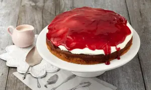 Eine köstliche Schneewittchen Torte mit weißer Sahne und glänzender roter Fruchtsauce, bereit zum Servieren.