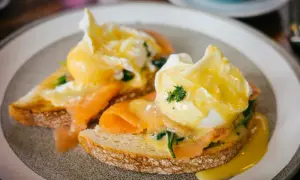 Zwei pochierte Eier auf Toast mit Lachs und Sauce Hollandaise. Ein köstliches pochierte Eier Rezept für ein perfektes Frühstück.