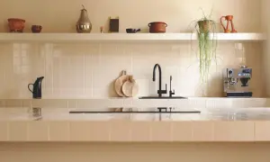 Encantadora cocina con azulejos claros, grifo negro y cafetera. Las últimas tendencias en azulejos para cocinas se reflejan en este diseño minimalista y funcional.
