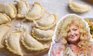 Magda Gessler prezentuje przepis na ciasto na pierogi. Na zdjęciu surowe pierogi na desce i uśmiechnięta restauratorka.