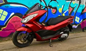 Czerwony skuter Honda PCX 125 na tle kolorowego graffiti. Mimo że jest to niezawodny model, warto pamiętać o jego awaryjności w ekstremalnych warunkach.