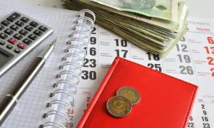 Kalkulator, długopis, stos banknotów i monety na kalendarzu. Przygotowanie do zapłaty opłaty od pozwu w postępowaniu upominawczym.