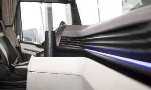 Un porte-gobelet noir avec le logo IVECO, un des indispensables du routier, est placé sur la console centrale d'un camion.