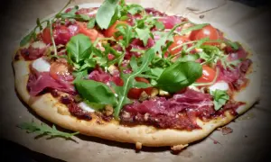En läcker bresaola pizza med körsbärstomater, ruccola och färsk basilika.