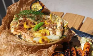 Fisk i folie med citron, dill och grönsaker, serverad med grillade morötter och fänkål.
