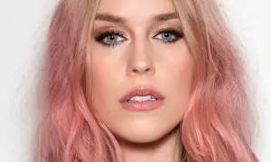 Kobieta z truskawkowym blond włosy, błękitnymi oczami i delikatnym makijażem.