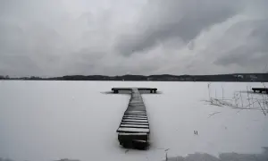 Zimowy pomost na zamarzniętym jeziorze. Ogniskowa 16 mm uchwyciła surowy krajobraz pod pochmurnym niebem.