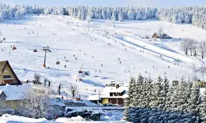 Stok narciarski w Karkonoszach, idealne miejsce na ferie zimowe 2026 dolnośląskie. Narciarze szusują po ośnieżonych zboczach, a kolejki linowe wwożą ich na szczyt.
