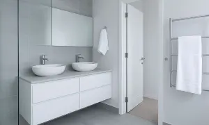 Modernos lavabos dobles sobre mueble blanco, espejo grande y azulejos grises. ¡Ideas para reformas de baños elegantes y funcionales!