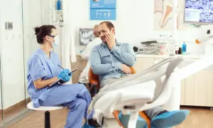 Pacjent u dentysty skarży się na ból, być może krwiak po znieczuleniu. Pielęgniarka notuje objawy.