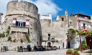 Antica torre del castello di Peschici, con tavoli all'aperto di un ristorante.