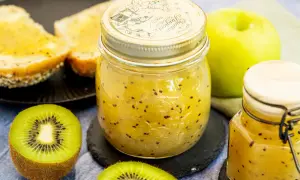 Ein Glas hausgemachte Kiwi-Marmelade mit frischen Kiwis und Toast.