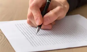 Dłoń pisze piórem na papierze. To może być wzór listu motywacyjnego, który pomoże Ci w karierze.