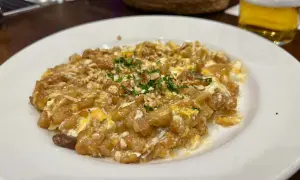 Delicioso revuelto de bacalao con trocitos de frutos secos y perejil picado, servido en un plato blanco.