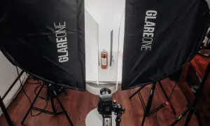 Profesjonalna fotografia produktowa jak zacząć? Zestaw oświetleniowy z dwiema lampami Glareone, aparatem i butelką w tle.