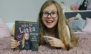Hejka, tu Lenka! Dziewczynka z okularami trzyma notatnik z napisem "Hejka, tu Lenka".