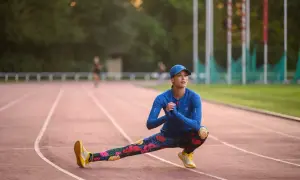Kobieta w kolorowych legginsach rozciąga się na bieżni.