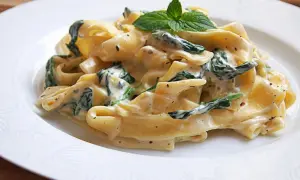 Pappardelle w kremowym sosie ze szpinakiem i mascarpone, udekorowane listkami mięty. Pyszne danie, które zachwyci każdego.