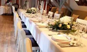Elegancko nakryty stół w restauracji, gotowy na przyjęcie. Zastanawiasz się, ile trwają chrzciny w restauracji? Zazwyczaj to kilka godzin, w zależności od programu.
