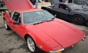 En röd De Tomaso Pantera bil med uppfälld huv. Bredvid står en svart bil med uppfällda dörrar.