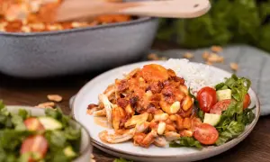En tallrik med flygande jakob originalrecept, ris och sallad. Kycklingen är täckt av en krämig sås med jordnötter och bacon.