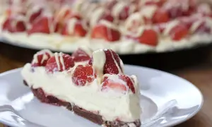 Pyszna tarta z truskawkami, udekorowana kremem i białym lukrem, kusi swoim wyglądem. Idealna na letnie popołudnie.