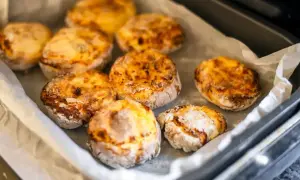 Upieczone placki z twarogu na blasze wyłożonej papierem do pieczenia.