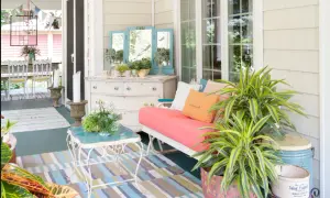 Porches sencillos y bonitos con un sofá coral, plantas exuberantes y un tocador vintage.