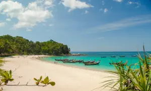 Piękne phuket plaże z turkusową wodą, białym piaskiem i łodziami dryfującymi na morzu.