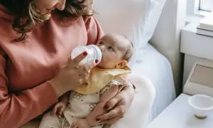 Mama karmi butelką dziecko, które ma problem z brakiem pokarmu po porodzie.