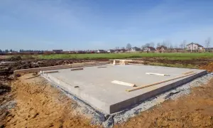 Budowa fundamentów cena: betonowa płyta na placu budowy, drewno przygotowane do dalszych prac.