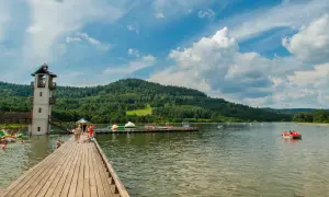 Słoneczny dzień nad zalewem Stara Morawa. Ludzie kąpią się, pływają na rowerach wodnych i relaksują na pomoście.