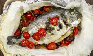 Orata al cartoccio con pomodorini, olive e capperi, cotta in forno.