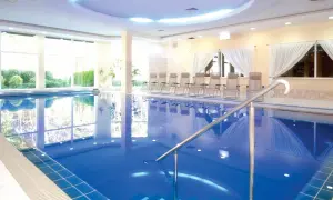 Relaks w hotelach nad morzem z basenem. Czysta, błękitna woda basenu, leżaki i widok na zieleń.