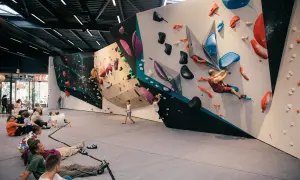 Des personnes se reposent au sol pendant que d'autres commencent l'escalade sur des murs colorés et texturés.