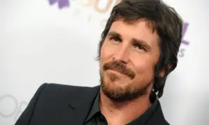 Christian Bale z brodą i w garniturze, znany z wielu świetnych christian bale filmów.