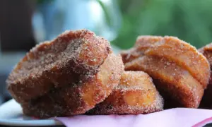 Süße Zwetschgen Bavesen, goldbraun frittiert und in Zimt-Zucker gewälzt, liegen auf einem rosa Tuch.