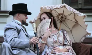 Para z epoki, mężczyzna w cylindrze i eleganckim garniturze, kobieta z wachlarzem i parasolką. Ich stylizacja to lalka opracowanie.