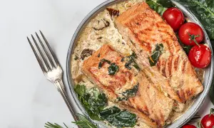 Deux pavés de saumon grillé dans une sauce crémeuse aux épinards, accompagnés de tomates cerises. Une recette saumon parfaite pour un dîner savoureux.
