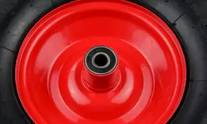Czerwone koło taczki z czarną oponą i łożyskiem w środku.