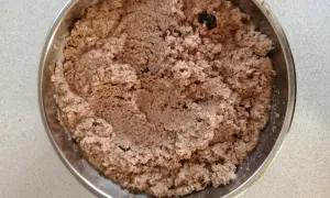 Masa makowa z bakaliami w metalowej misce. Wygląda jakby zawierała biały mak, rodzynki i inne dodatki.